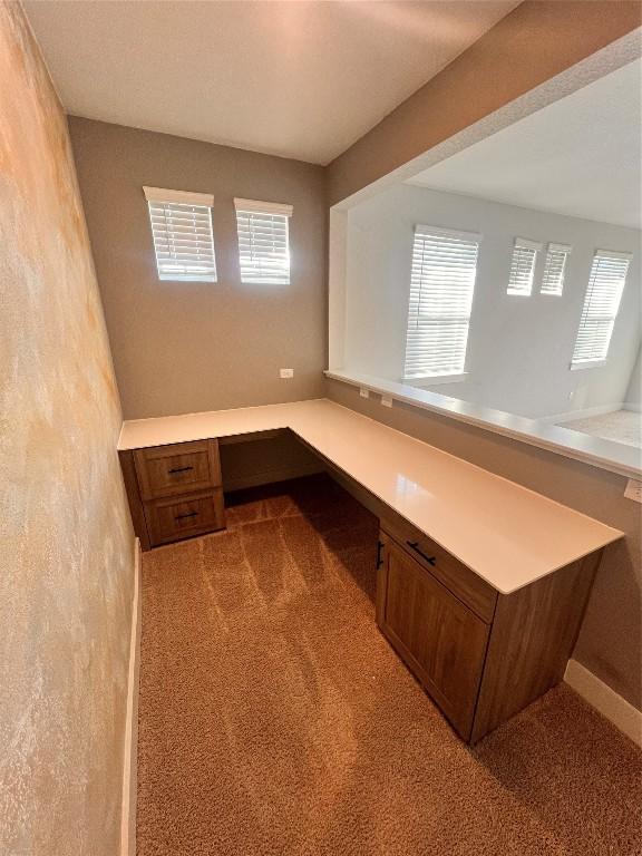 unfurnished office featuring built in desk and light colored carpet