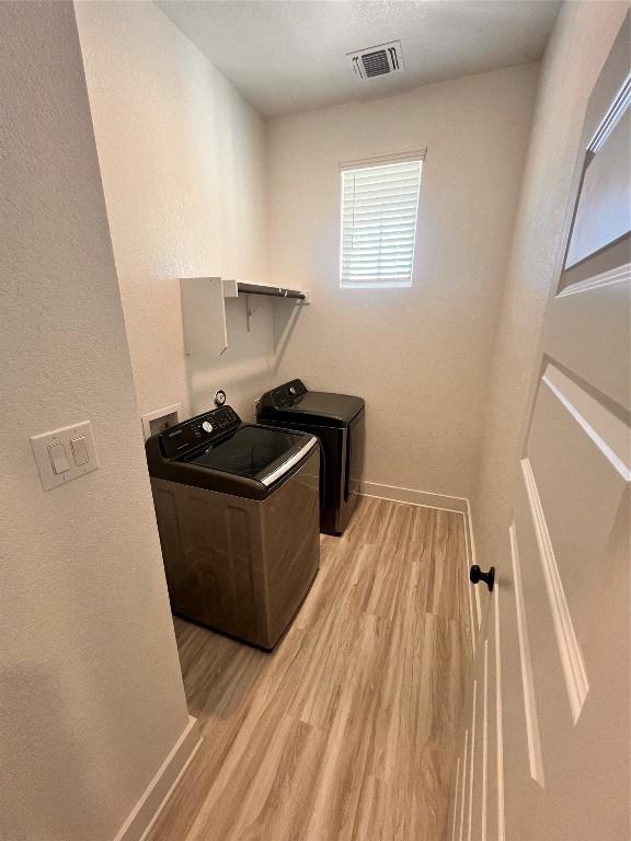 laundry area with washer and dryer and light wood-type flooring