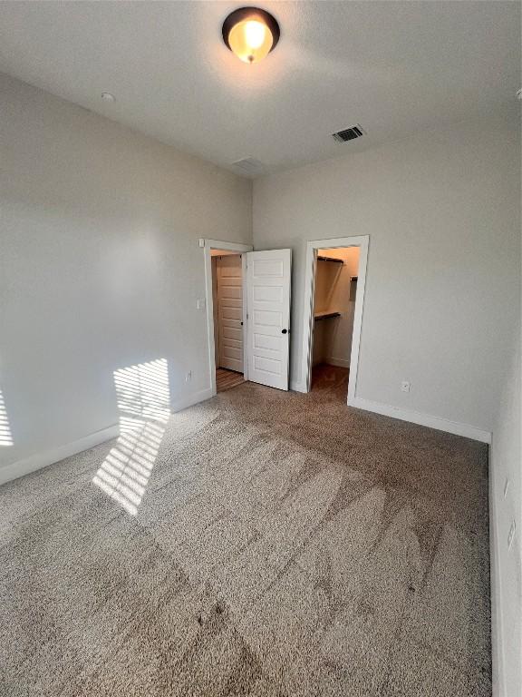 unfurnished bedroom with a spacious closet, carpet floors, and a closet