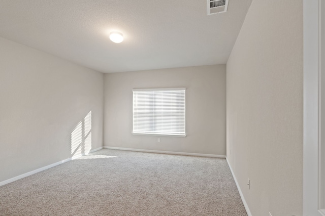 spare room featuring light carpet and a textured ceiling