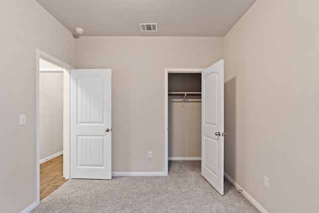 unfurnished bedroom with light carpet and a closet