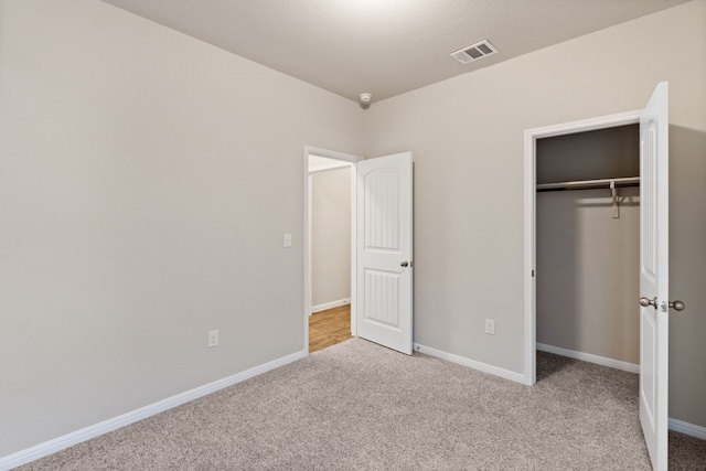 unfurnished bedroom with light carpet and a closet