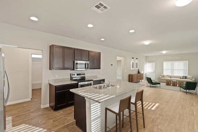 kitchen featuring light hardwood / wood-style flooring, stainless steel appliances, a center island with sink, and sink