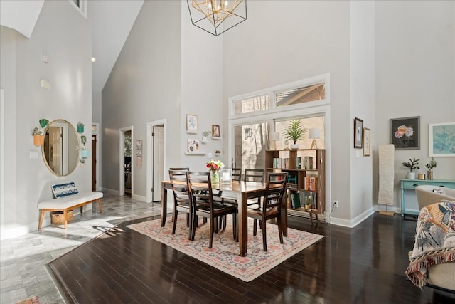 dining space featuring a high ceiling, dark wood-type flooring, and a notable chandelier