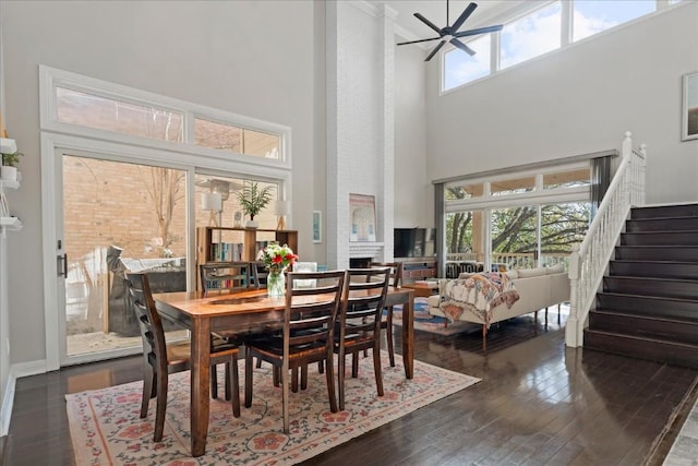 dining space featuring a fireplace, a wealth of natural light, dark hardwood / wood-style flooring, and a high ceiling