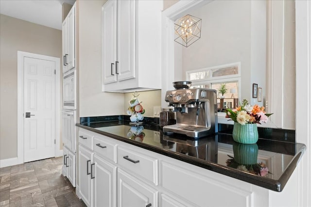 bar with white cabinetry, white appliances, and a notable chandelier