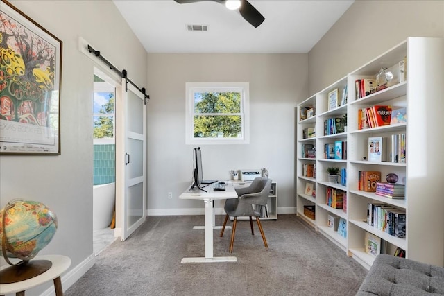 office space with a barn door, carpet floors, and ceiling fan