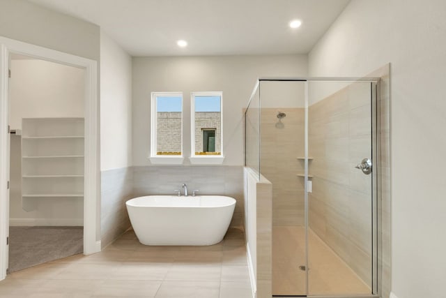 bathroom with a shower stall, recessed lighting, tile walls, and a soaking tub