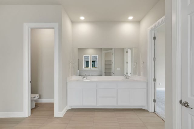 bathroom featuring a sink, toilet, double vanity, and recessed lighting
