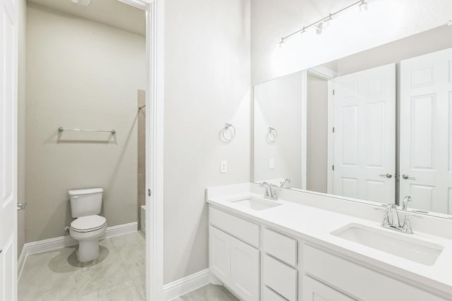 bathroom with double vanity, baseboards, a sink, and toilet