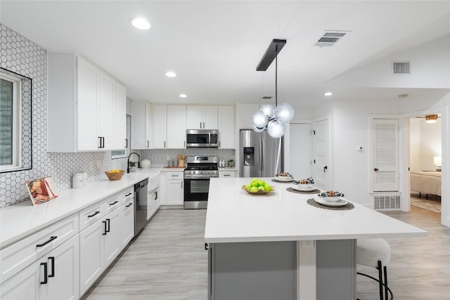 kitchen featuring light wood-type flooring, appliances with stainless steel finishes, a center island, and white cabinetry