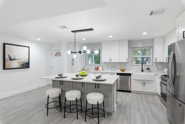 kitchen featuring white cabinets, a center island, stainless steel appliances, and pendant lighting