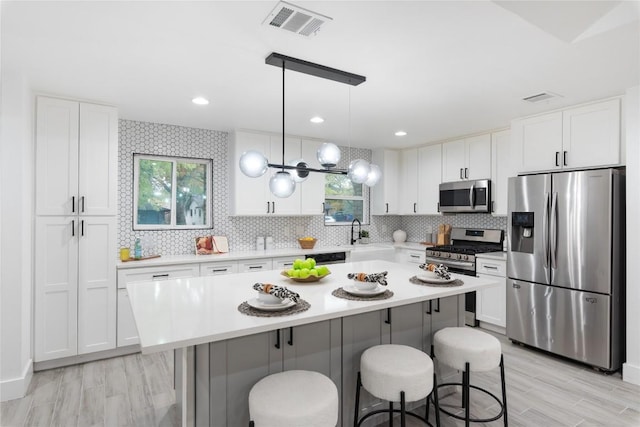 kitchen with appliances with stainless steel finishes, white cabinetry, a kitchen island, and a healthy amount of sunlight