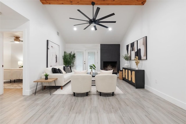 living room featuring french doors, beam ceiling, high vaulted ceiling, light hardwood / wood-style flooring, and a fireplace