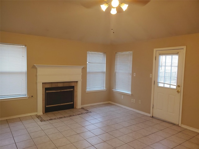 unfurnished living room with a tile fireplace, ceiling fan, and light tile patterned flooring