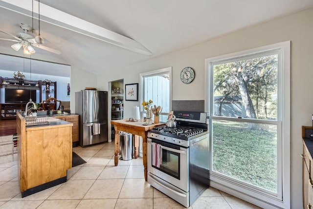 kitchen featuring ceiling fan, light tile patterned floors, vaulted ceiling, and appliances with stainless steel finishes