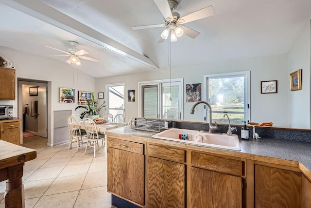 kitchen with lofted ceiling with beams, ceiling fan, light tile patterned floors, and sink