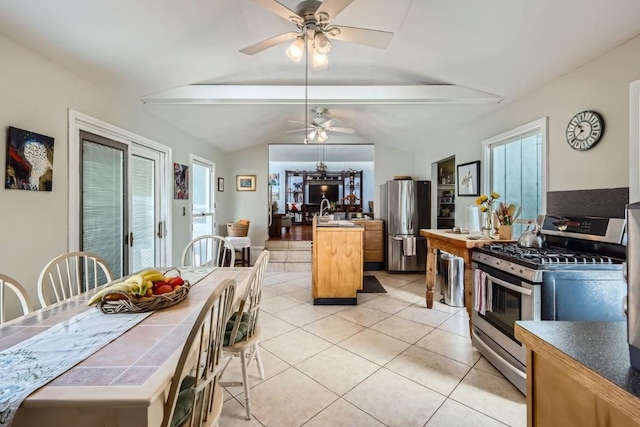 kitchen with light tile patterned floors, vaulted ceiling with beams, stainless steel appliances, and plenty of natural light