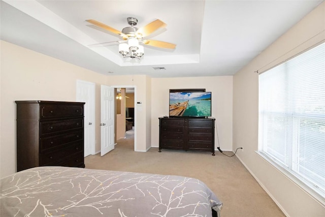 carpeted bedroom featuring ceiling fan and a raised ceiling