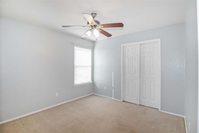 unfurnished bedroom featuring ceiling fan, light carpet, and a closet