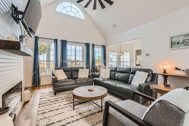 living room featuring light hardwood / wood-style floors, high vaulted ceiling, and ceiling fan