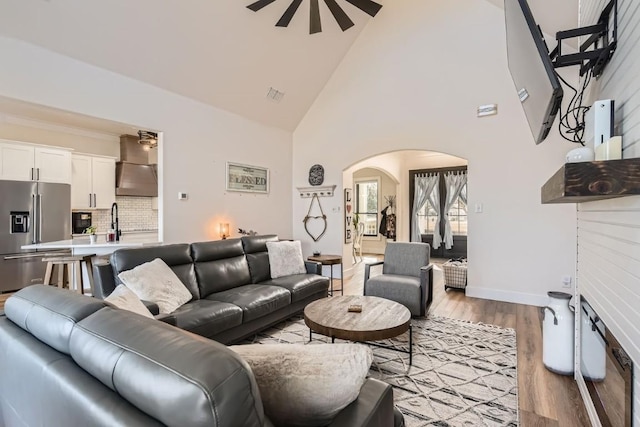 living room featuring light hardwood / wood-style floors, high vaulted ceiling, and ceiling fan