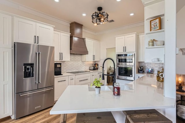 kitchen with white cabinets, light wood-type flooring, custom range hood, and appliances with stainless steel finishes