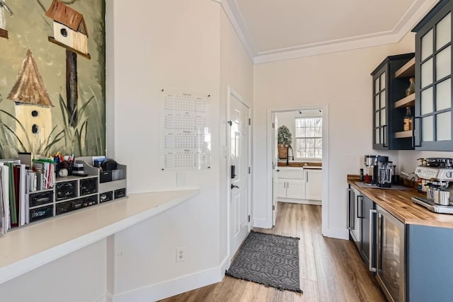 kitchen with kitchen peninsula, crown molding, hardwood / wood-style floors, wine cooler, and butcher block counters