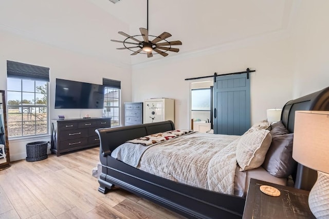 bedroom featuring multiple windows, ceiling fan, light hardwood / wood-style floors, and a barn door