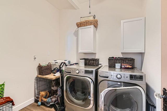 washroom with washer and dryer, cabinets, and wood-type flooring