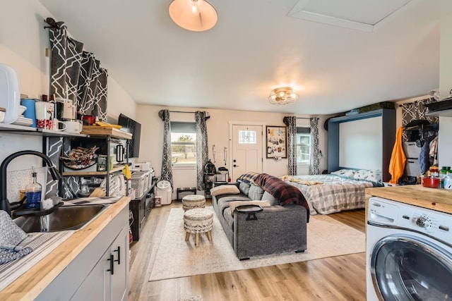 bedroom featuring sink, washer / clothes dryer, and light hardwood / wood-style flooring