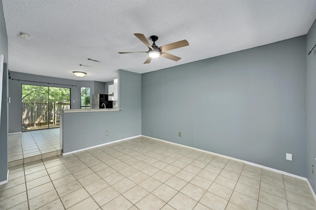 empty room featuring a textured ceiling, ceiling fan, and light tile patterned flooring