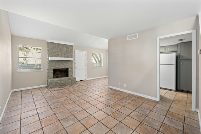 unfurnished living room with a wealth of natural light, a fireplace, and light tile patterned floors