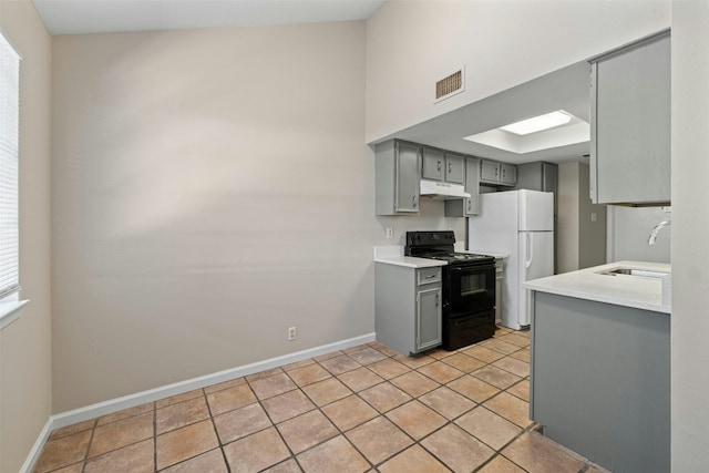 kitchen featuring electric range, gray cabinets, light tile patterned flooring, and white refrigerator