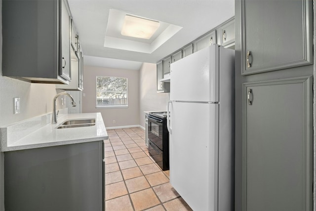 kitchen featuring gray cabinetry, sink, a raised ceiling, black electric range, and white fridge