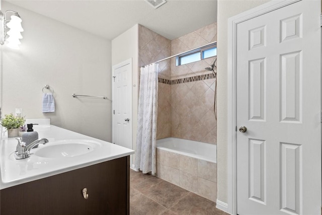 bathroom with double vanity, visible vents, tile patterned flooring, a sink, and tiled shower / bath combo