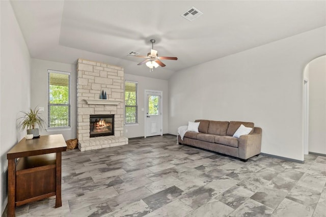 living room with a stone fireplace, ceiling fan, and lofted ceiling