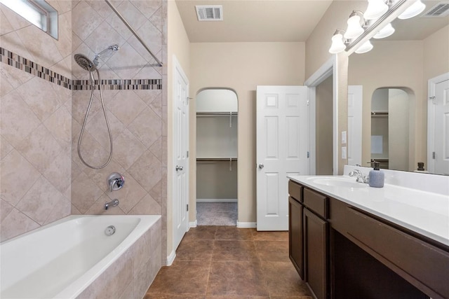 bathroom featuring vanity, tile patterned flooring, tiled shower / bath combo, and visible vents