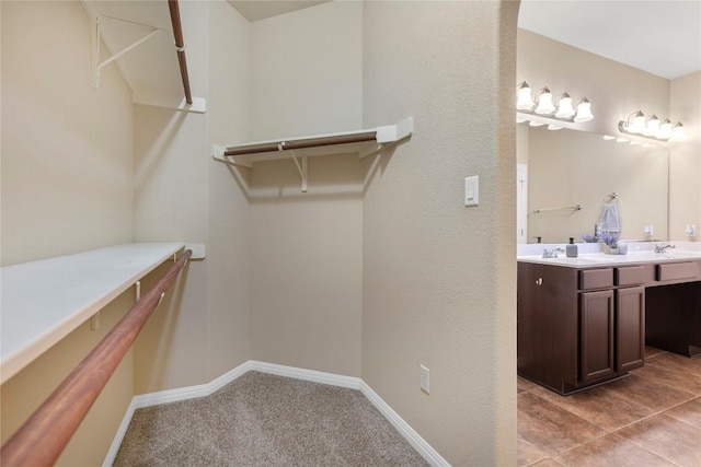 spacious closet featuring light colored carpet and a sink