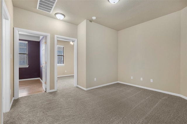 empty room with carpet flooring, baseboards, and visible vents