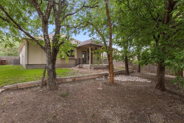 exterior space with fence, stucco siding, central AC, and a front lawn