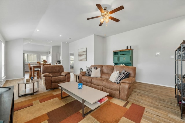 living room featuring vaulted ceiling, light hardwood / wood-style flooring, and ceiling fan