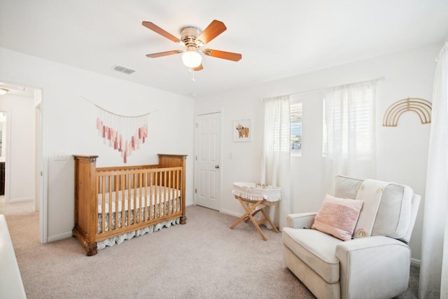 bedroom with a crib, light carpet, a closet, and ceiling fan