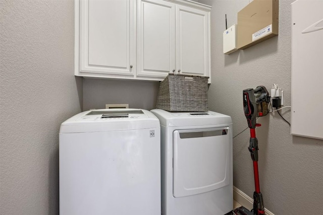 clothes washing area featuring washing machine and dryer and cabinets