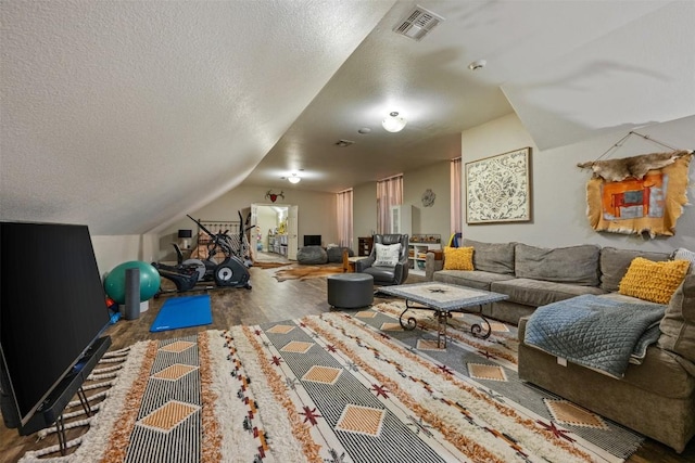 exercise room featuring hardwood / wood-style flooring, vaulted ceiling, and a textured ceiling