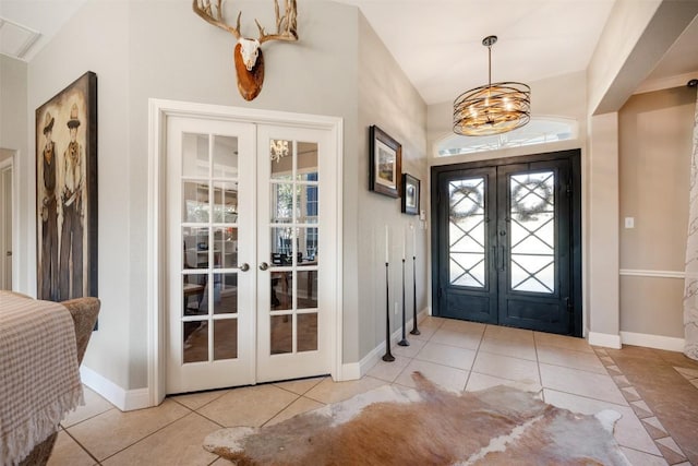 entrance foyer with plenty of natural light, light tile patterned floors, a notable chandelier, and french doors