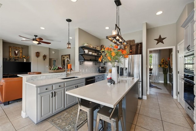 kitchen featuring sink, gray cabinetry, tasteful backsplash, black appliances, and a kitchen island