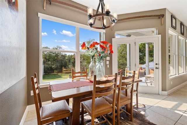 sunroom / solarium with a healthy amount of sunlight, an inviting chandelier, and french doors