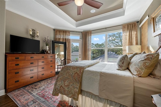 bedroom featuring crown molding, ceiling fan, wood-type flooring, and a tray ceiling