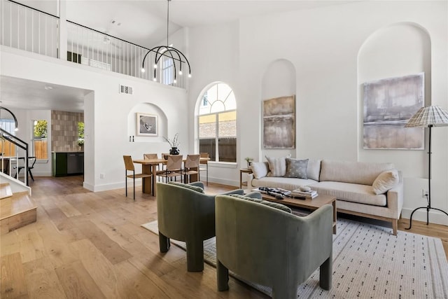 living room featuring a chandelier, light hardwood / wood-style floors, high vaulted ceiling, and a wealth of natural light